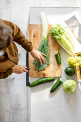 Woman cooking some food, cutting fresh ingredients on the cutting board on the kitchen, view from...