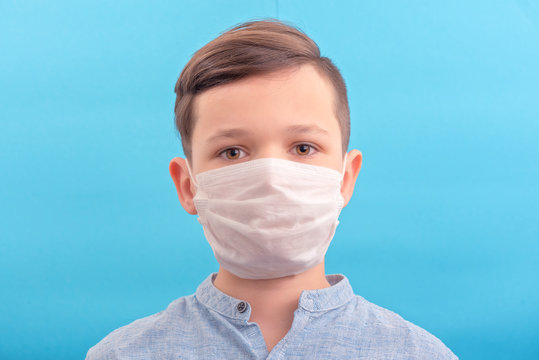 Handsome brunette boy in medicine face mask over blue background