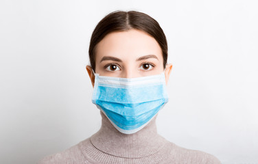 Portrait of young woman wearing medical mask at white background. Protect your health. Coronavirus...