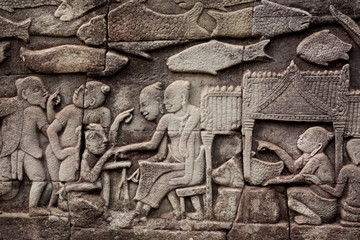 Fortune telling at the market square, bas-relief of the 12th century Bayon temple, Cambodia. Historical walls in Angkor. UNESCO world heritage site