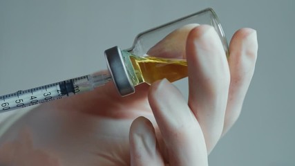 The needle of the syringe takes medicine from glass vial. Filling syringe from vial. female doctor picks up a syringe. Close-up. The epidemic situation - Powered by Adobe