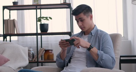 Amazed guy watching online videos on cellphone at home - Powered by Adobe