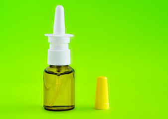 Nasal spray in a glass bottle on a green empty background. The concept of treatment for flu, colds...