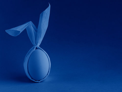 Easter egg with ears on a blue background. toned in modern trendy color classic blue