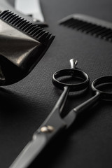 On a black surface are old barber tools. vintage manual hair clipper, razor, comb, hairdressing...
