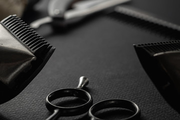 On a black surface are old barber tools. Two vintage manual hair clipper, razor, comb, shaving brush, hairdressing scissors. black monochrome. horizontal