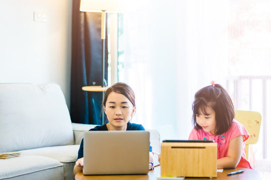 Covid-19 Coronavirus and Learning from home, Home school kid concept.Little asian girl study with online learning and asian mother work from home with laptop.Quarantine and Social distancing concept.