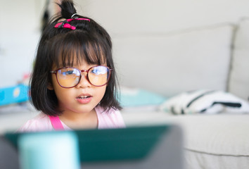 Covid-19 Coronavirus and Learning from home, Social distancing.Little asian girl talking and learning math with video call app with tablet and wearing eyes glasses stay online at home, Stay at home.