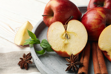 Tray with apple and cinnamon, and towel on wooden background, close up