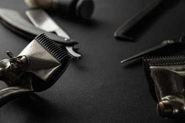 On a black surface are old barber tools. Two vintage manual hair clipper, razor, shaving brush, hairdressing scissors. black monochrome. horizontal