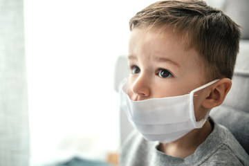 Little boy waring a mask to proctect him from the corona virus covid-19 / 2019-nCov while looking at copyspace concept. Closeup face, Little children boy using medicine healthcare mask