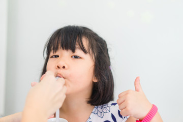 Little asian little girl accept to drink medicine syrup with syringe from mother at home.illness...