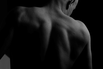 Fototapeta na wymiar Back. The back of the man. Man holding a chain on his back in both hands. Chain. Black and white photo. Power. Sports Hall.