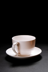 A white ceramic coffee cup stands on a black background