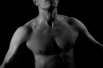 Fototapeta na wymiar The pumped up body of a man. Black and white background. Sport. Clothing. Body. Beauty and fashion.