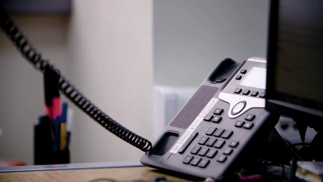 Close up slow motion shot of an employee answering an old internal wire phone