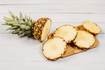 Fototapeta na wymiar Ripe pineapple cut on slices on wooden background