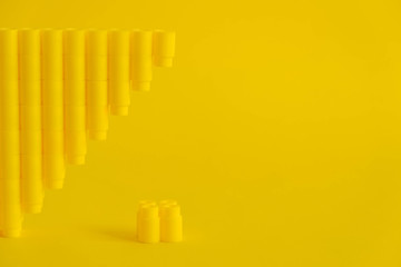 Yellow plastic building blocks in the shape of a pyramid on yellow background. Background of...