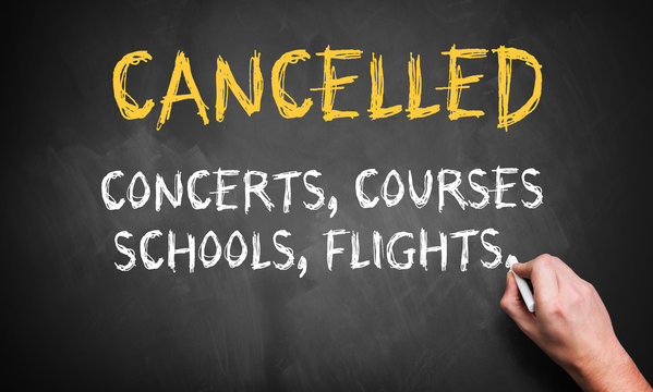 hand writing message CANCELLED, CONCERTS, COURSES, SCHOOLS, FLIGHTS on blackboard