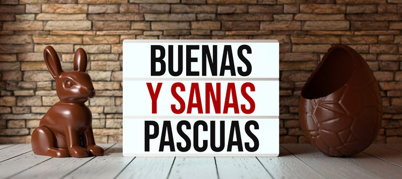 lightbox with message HAPPY HEALTHY EASTER in Spanish in front of a brick wall on wooden floor