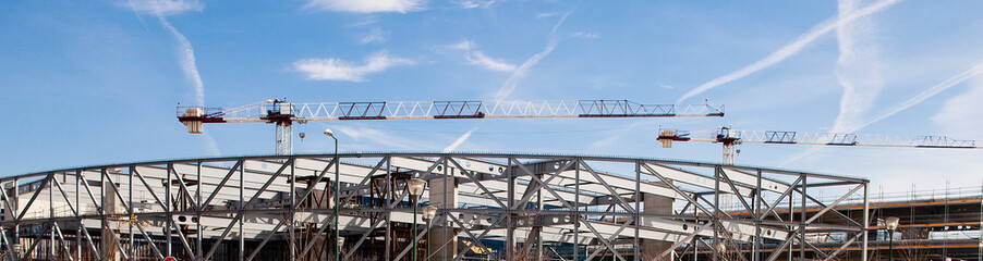 Obraz premium Iron structure and construction crane with blue sky and clouds