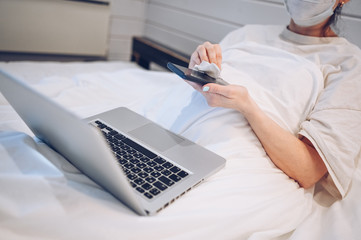 Unrecognizable woman in face mask in bedroom during coronavirus isolation home quarantine cleaning...