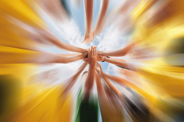 Low angle shot of a group of sports team forming a huddle with their hands outdoor. Sports team stacking hands together before the game