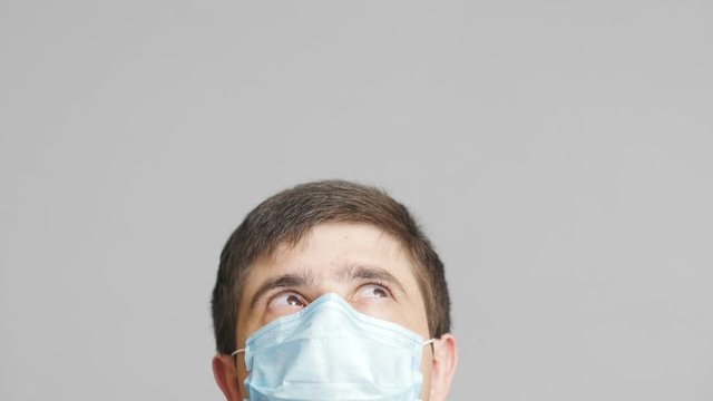 head of a young man in protective surgical mask looking up and following news, concept of health and medicine,emotions of confusion and perplexity