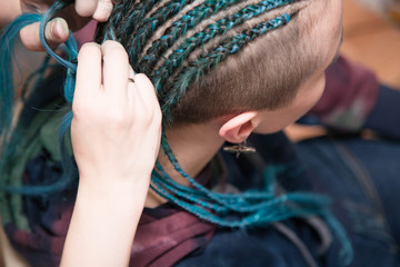 The process of braiding cornrows using turquoise kanekalon fibres