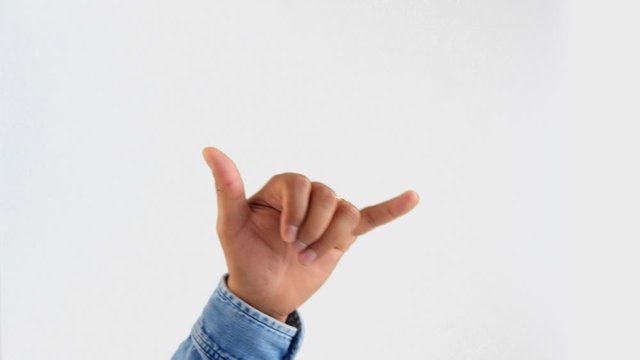 male hand in jeans shirt do a shaka hand gesture on white