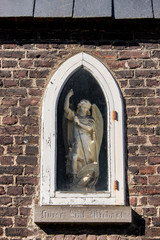 Gent, Belgium - March 22, 2020: Saint Michael statue found in a wall in the Saint Elisabeth beguinage. Unesco listed.