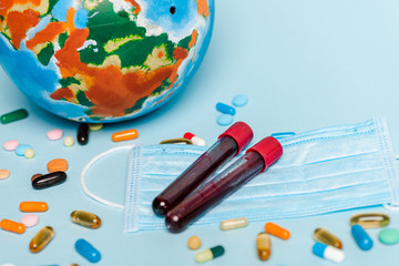 test tubes with blood samples near medical mask, pills and globe on blue background, coronavirus...