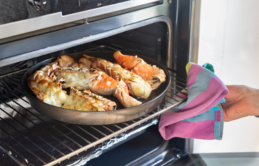To remove the grilled lobster from the oven with a dish towel