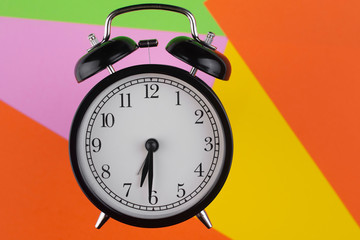 Black alarm clock on a colorful background. Free space for an inscription.