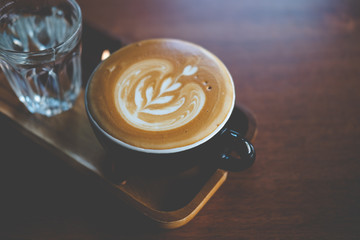 Close up of cup of hot latte art coffee served with cold water
