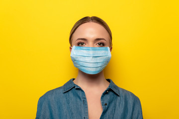 young woman in medical mask on yellow background, coronavirus concept