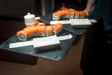 the waiter carries in his hands two plates of sushi with red fish