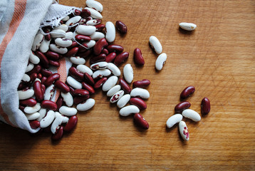 Ripe red and white beans sprinkled on a wooden table