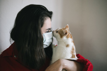 Fototapeta na wymiar Girl in a medical mask with a cat