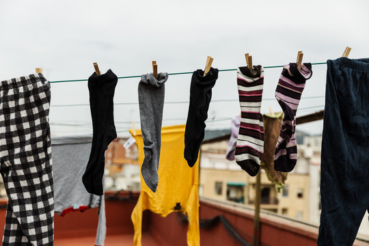 foto sin personas de ropa tendida secandose en un tejado en el exterior, d&iacute;a nublado soleado, camisetas, chandal, calcetines, cogido con pinzas de tender de madera