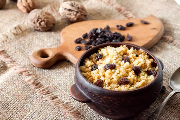 Sweet millet porridge with dark raisins in ceramic rustic bowl