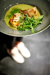 grilled fish in a plate with herbs and micro green