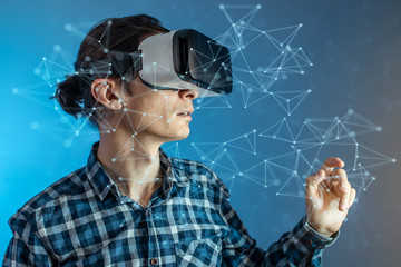 Man wearing virtual reality glasses watching at a 3D visualization in an abstract polygonal grid in a futuristic style.