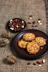 Homemade peanut cookies on a brown plate with raw peanuts in background