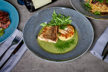 grilled fish in a plate with herbs and micro green