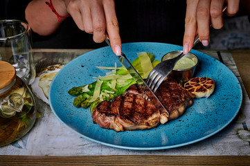 man eats steak in a plate on a table in a restaurant