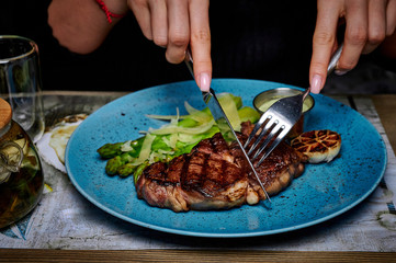 man eats steak in a plate on a table in a restaurant