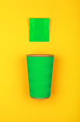 Green paper coffee cup over yellow