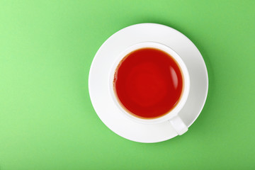 White cup of black or red fruit tea over green