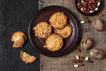 Homemade peanut cookies on a brown plate with raw peanuts in background